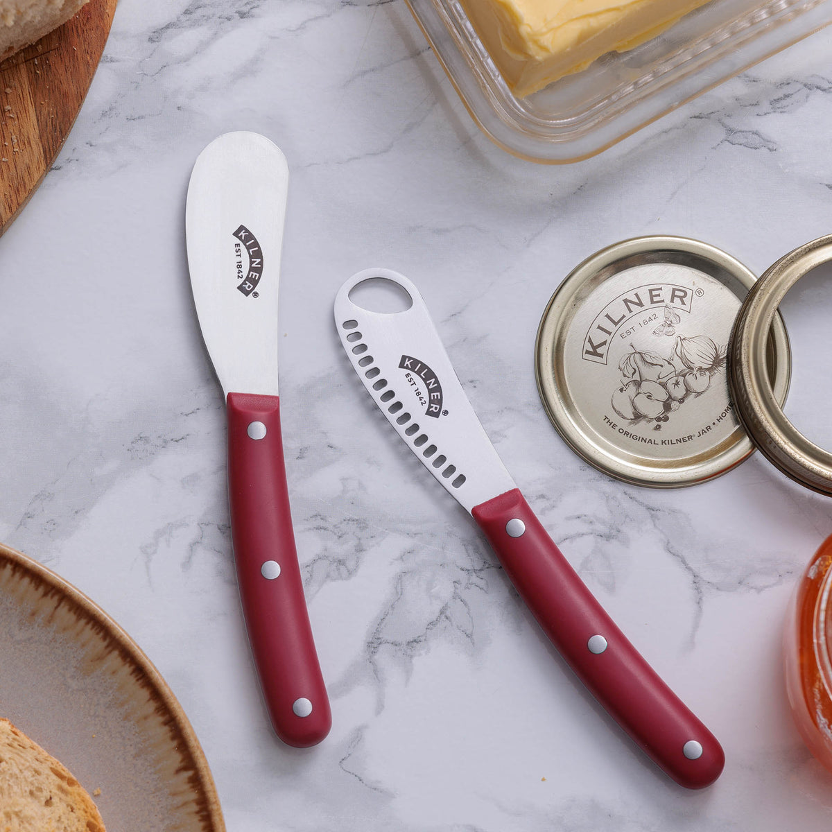KILNER buttermesser with red handle and two grips, designed for spreading butter smoothly.