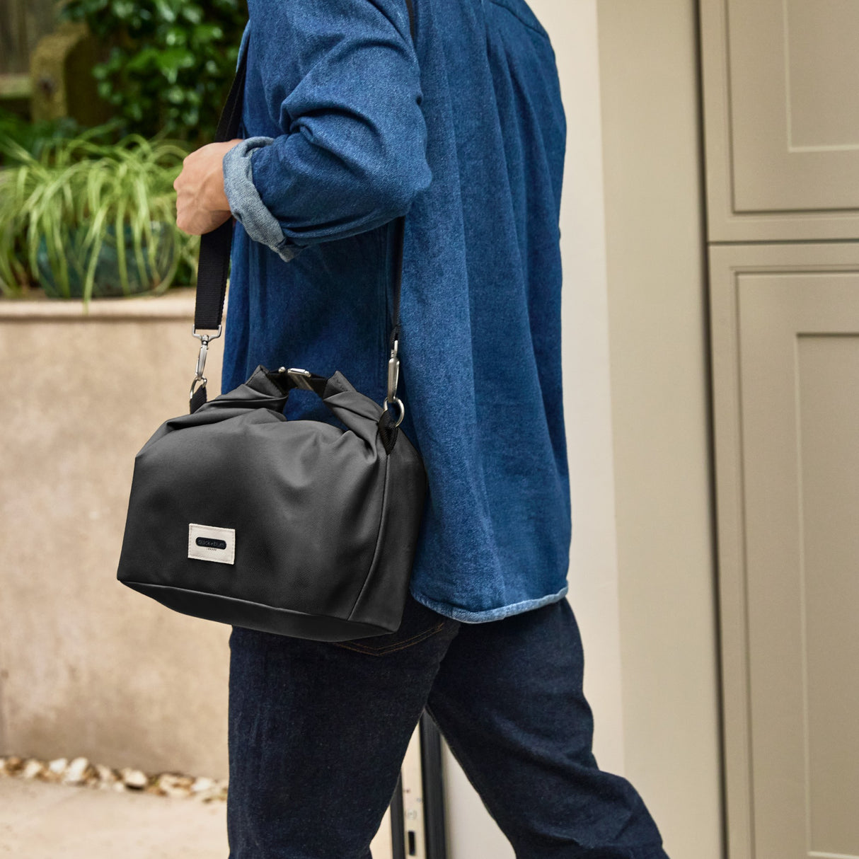 Black+Blum insulated lunchbag with shoulder strap, large black fabric, designed for carrying lunch in a stylish, practical way.