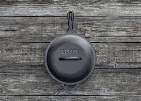 Black LODGE Classic lid for cookware, shown resting on a stove or cookware surface. Durable and heat-resistant kitchen accessory.